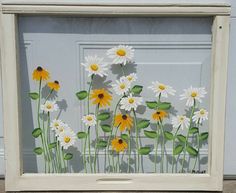 a painting of white and yellow daisies in front of a gray door with green leaves