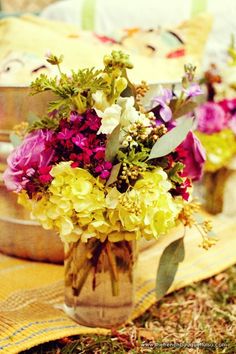 a vase filled with lots of flowers on top of a cloth covered table next to other plates