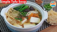 a white bowl filled with soup next to crackers and other food on a table