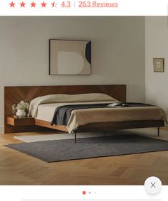 a bed sitting on top of a wooden floor next to a wall with pictures above it