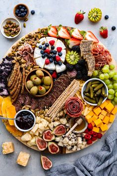 an assortment of cheeses, crackers, fruit and nuts on a platter