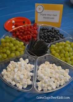 grapes, raspberries, and marshmallows are arranged in trays on a table