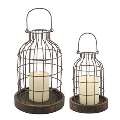 two metal cages with candles in them sitting on top of a wooden stand next to each other