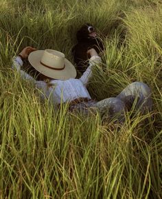 a person laying in the grass with a hat on