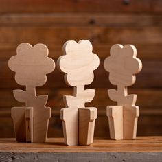 three wooden cutouts of flowers sitting on top of a wood table next to each other