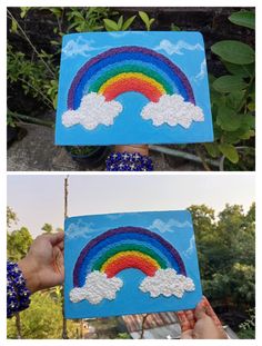 someone is holding up a painting with clouds and a rainbow on it