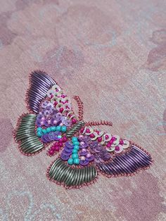 a close up of a butterfly brooch with beads on it's back end