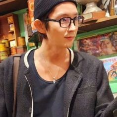 a man wearing glasses and a beanie looks at his cell phone in a store