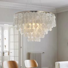 a chandelier hanging from the ceiling in a room with white walls and chairs