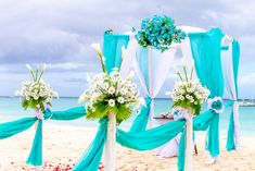 an outdoor wedding setup on the beach with blue and white draping draped over it