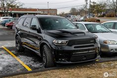 several cars parked in a parking lot with snow on the ground and one is black