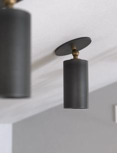 three light fixtures hanging from the ceiling in a room with white walls and gray ceilings