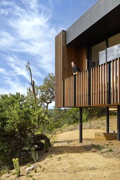 a man standing on the balcony of a wooden house in the middle of a desert