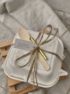 two wooden spoons tied with twine on top of white plates and napkins