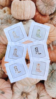 four embroidered napkins on top of pumpkins in the shape of boots and boots