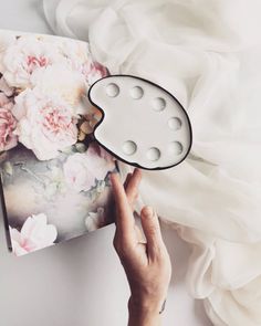 a person holding up a white clock with flowers on it