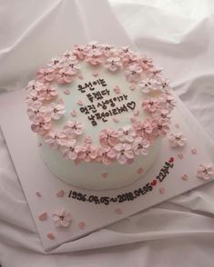 a birthday cake decorated with pink flowers and the words happy birthday written in black on it