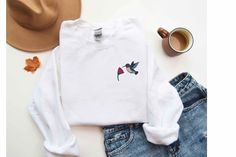 Embroidered cute bird sweater 🌸🐦 Made from 100% ethically grown US cotton, this unisex hummingbird sweatshirt combines comfort with style, making it a standout piece. Its relaxed fit makes it perfect for casual outings and sparking conversations. The ribbed knit collar retains its shape even after washing, and there are no itchy side seams for added comfort.  The minimalistic hummingbird & flower design is embroidered on the left side of the chest using six standard-colored threads: green, red Casual Sweater With Relaxed Fit As Gift, Casual Relaxed Fit Sweater As Gift, Casual Relaxed Fit Sweater, Bird Sweater, Hummingbird Gifts, Boho Pullover, Cozy Boho, Cute Bird, Cute Birds