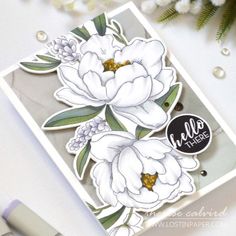 a close up of a card with flowers on it and a pen next to it