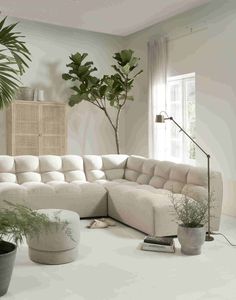 a living room filled with lots of furniture next to potted plants on top of a white floor