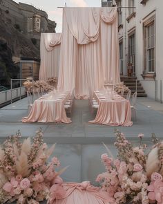 an outdoor wedding setup with pink flowers and drapes