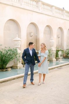 a man and woman holding hands in front of a fountain