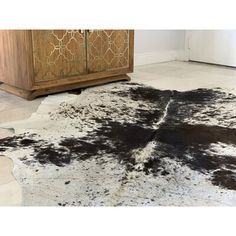 a black and white cowhide rug on the floor in front of a wooden cabinet