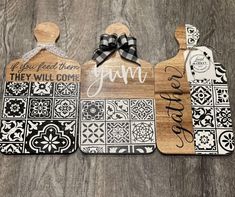 three wooden cutting boards with black and white designs on them, one has a bow