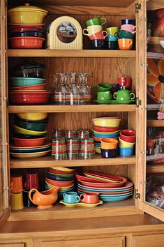 a wooden cabinet filled with lots of colorful dishes