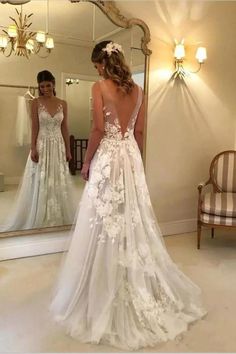 a woman standing in front of a mirror wearing a wedding dress with flowers on it