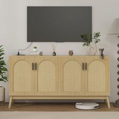 a tv mounted on the wall above a wooden cabinet with wicker doors and handles