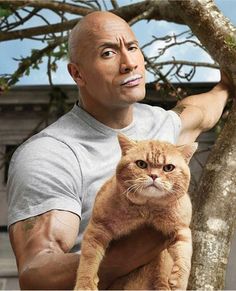 a man holding a cat up to his face while standing next to a tree and looking at the camera