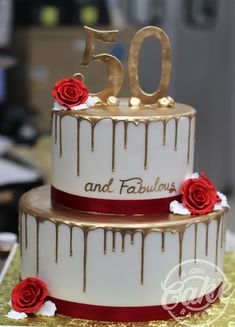 a 50th birthday cake decorated with red roses and dripping chocolate