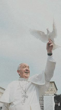 a man holding a white bird in his right hand while standing next to a camera