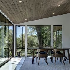 a dining room with large windows and wooden ceiling