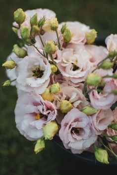 a bunch of flowers that are sitting in a vase on the ground with grass behind them