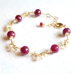 Luscious red rubies are featured in this artisan style jewelry. Accented with beautiful white freshwater pearls. Set in 14k gold filled findings. Give a gift that she will treasure for a lifetime. Exquisite ruby bracelet is perfect for women who love artisan jewelry, love red gemstones, and for women born in July since ruby is her birthstone. Bracelet Details: - Bracelet Length is adjustable from 7 to 8 inches (17.78 cm to 20.32 cm) - Handmade with 14k gold filled or sterling silver wire, chain Ruby And Pearl, Pearl Bracelet Gold, Ruby Bracelet, Birthstone Bracelet, Wedding Jewelry Bracelets, Red Gemstones, Wedding Anniversary Gift, White Freshwater Pearl, July Birthstone