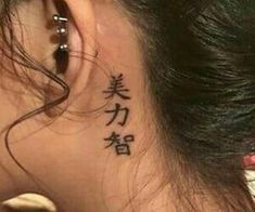 the back of a woman's neck with chinese characters on it and behind her ear