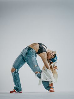 a woman in ripped jeans is dancing with her hands behind her back and head down