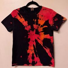 a red and black tie dye shirt hanging on a wall