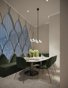 a dining room with green chairs and a round table in front of a large window