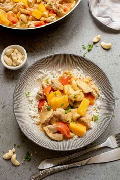 a plate with rice, chicken and vegetables on it next to a bowl of cashews