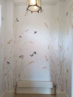 an empty hallway with wallpaper decorated with birds and grass in the corner, along with a light fixture