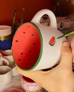 a person is painting a watermelon teapot