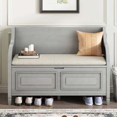 a gray bench with some shoes underneath it and a painting on the wall behind it