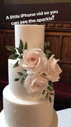 a white wedding cake with flowers on the top and words above it that read, a little phone vid so you can see the sparkle