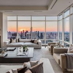 a living room filled with lots of furniture and large windows overlooking the cityscape