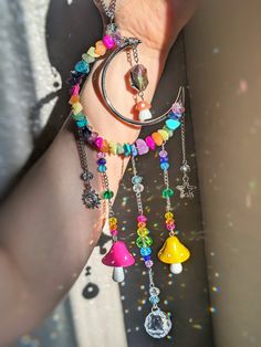 a woman's arm with several charms attached to it and beads hanging from the wrist