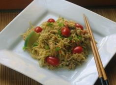 a white plate topped with noodles and vegetables next to chopsticks