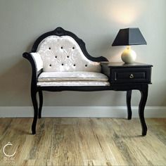 a black and white chair sitting next to a table with a lamp on top of it